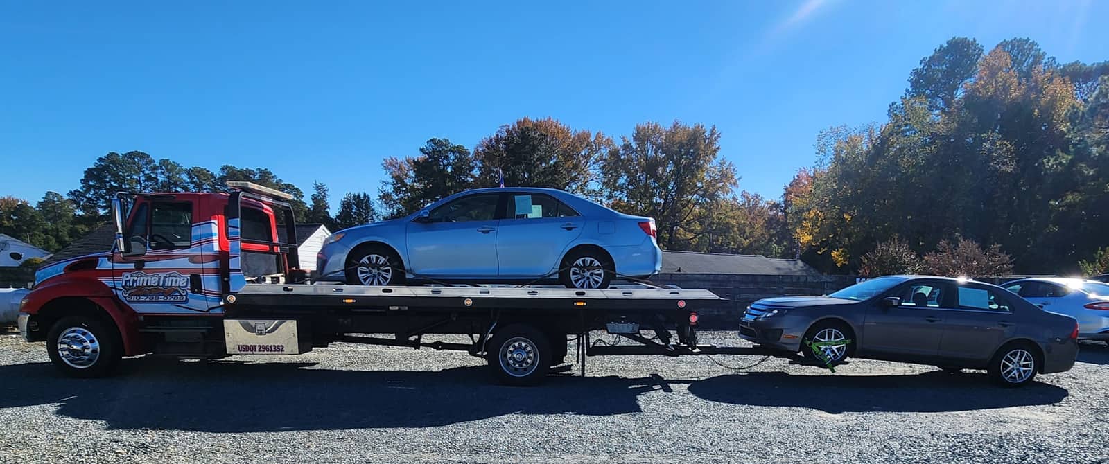 Prime Time flatbed carrying one sedan while towing a second vehicle behind it, southeastern North Carolina